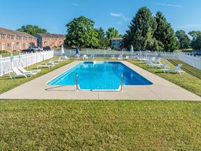 Wrightsville apartment for rent - A large swimming pool surrounded by lawn chairs and a white fence.