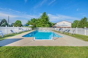 York apartment for rent - A pool surrounded by lawn chairs and a white fence.