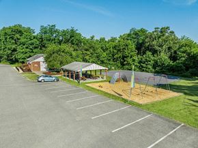 Manchester apartment for rent - A parking lot with a playground and a building in the background.