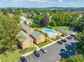 Ephrata apartment for rent - A parking lot with cars and a building with a pool in the background.