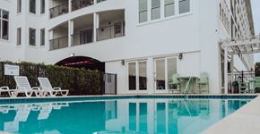 Biloxi apartment for rent - A white building with a pool in front.