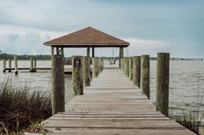 Biloxi apartment for rent - A wooden pier leads to a gazebo in the middle of a body of water.