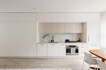 Vancouver apartment for rent - A modern kitchen with white cabinets and a wooden table.