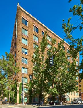 Seattle apartment for rent - A tall brick building with many windows and trees in front.