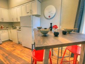 Seattle apartment for rent - A kitchen with a white refrigerator, white cabinets, wooden table, and red chairs.