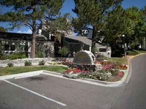 Englewood apartment for rent - A stone sign surrounded by trees sits in front of a residential building.