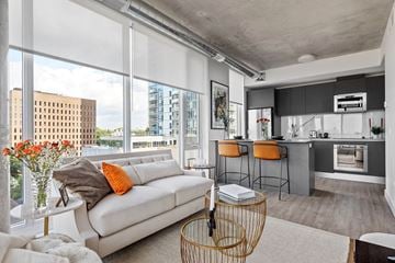 Ottawa apartment for rent - A modern living room with a white sofa and a kitchen area in the background.