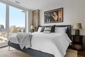 Ottawa apartment for rent - A bedroom with a large bed and a city view through the window.