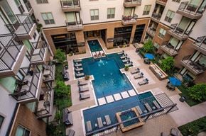 Richardson apartment for rent - A large swimming pool surrounded by lounge chairs and balconies of apartment buildings.