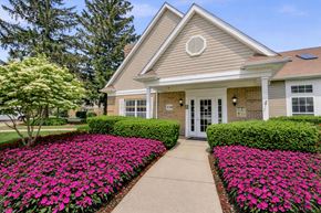 Ann Arbor apartment for rent - A house with a grey roof and a white door is surrounded by a flower bed.