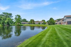 Ann Arbor apartment for rent - A serene landscape with a lake, grass, and residential buildings.