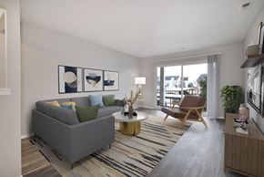 Waterford Twp apartment for rent - A living room with a grey couch, a wooden chair, a coffee table, and a striped rug.