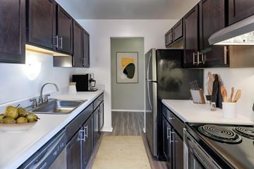 Livonia apartment for rent - A kitchen with black cabinets and a stainless steel refrigerator.