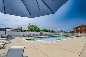 Sterling Heights apartment for rent - A pool area with a blue umbrella and a white fence.