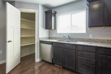 Herriman townhouse for rent - A kitchen with dark wood cabinets and a granite countertop.