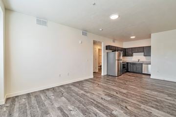 Magna apartment for rent - A kitchen with a refrigerator, oven, and sink is visible through a doorway.