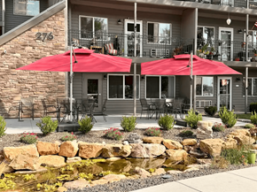 Eagle apartment for rent - A patio with red umbrellas and a water feature in front of a building.