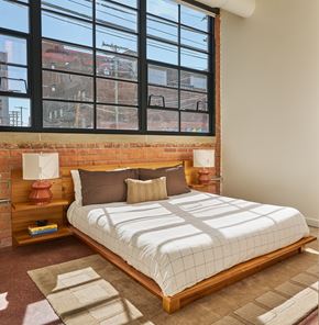Detroit apartment for rent - A bedroom with a large bed and a brick wall.
