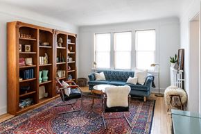 Detroit apartment for rent - A living room with a blue couch, a rug, and a bookshelf.