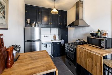Detroit apartment for rent - A kitchen with a wooden table and black cabinets.