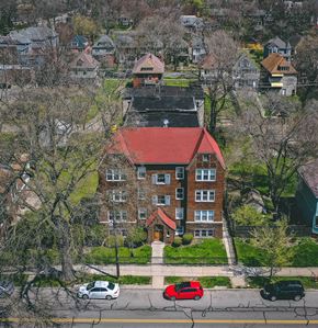 Detroit apartment for rent - A red car is parked on the street in front of a brick building.