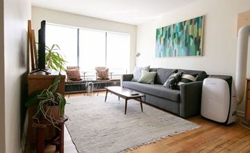 Detroit apartment for rent - A living room with a grey couch and a large painting on the wall.