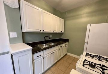 Detroit apartment for rent - A kitchen with white cabinets and a white fridge.
