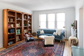 Detroit apartment for rent - A living room with a blue couch, a rug, and a bookshelf.