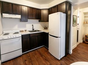 Detroit apartment for rent - A kitchen with white appliances and dark wood cabinets.