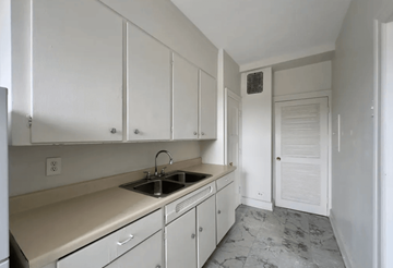 Detroit apartment for rent - A kitchen with white cabinets and a marble floor.