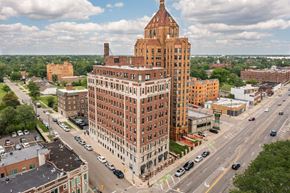 Detroit apartment for rent - A large red brick building with a tower sits in the middle of a busy intersection.