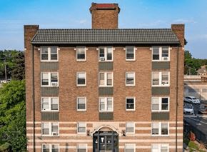 Detroit apartment for rent - A tall brick building with a black door and windows.