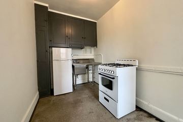 Detroit apartment for rent - A kitchen with a white stove and black cabinets.