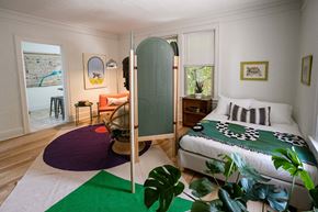 Detroit apartment for rent - A bedroom with a bed, a chair, a table, and a green rug.