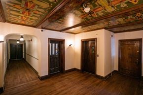 Detroit apartment for rent - A hallway with wooden floors and a ceiling with a colorful mural.