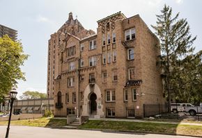 Detroit apartment for rent - A large brown building with a black fence in front.
