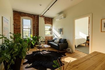 Detroit apartment for rent - A living room with a black couch and a wooden floor.