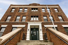 Detroit apartment for rent - A red brick building with a black door and windows.