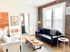 Detroit apartment for rent - A living room with a black couch, a white chair, and a wooden coffee table.