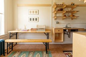 Detroit apartment for rent - A kitchen with a table and chairs and a shelf with various items on it.