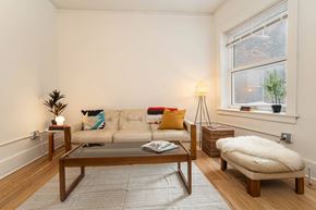 Detroit apartment for rent - A living room with a white couch, a coffee table, and a small tree.