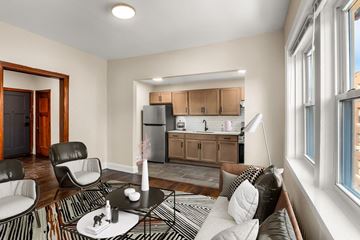 Detroit apartment for rent - A modern living room with a black and white striped rug and a round table with a vase of flowers on it.