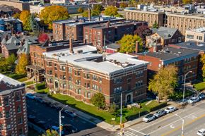Detroit apartment for rent - A large red brick building with a green roof sits in the middle of a city street.