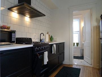 Detroit apartment for rent - A kitchen with black cabinets and a white tiled wall.