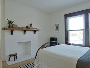 Detroit apartment for rent - A bedroom with a bed, a fireplace, and a window.