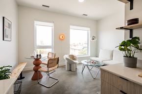 Detroit apartment for rent - A living room with a white couch, a wooden table, and a chair.