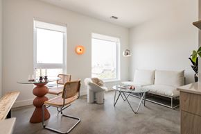Detroit apartment for rent - A living room with a white couch, a wooden table, and a chair.