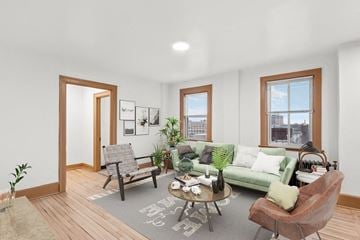 Detroit apartment for rent - A living room with a green couch, a grey armchair, a wooden floor, and a grey rug with a white design.