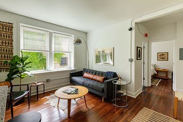 Detroit apartment for rent - A living room with a grey couch and a wooden table.