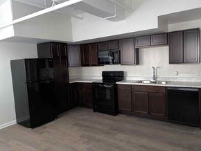 Evansville apartment for rent - an empty kitchen with black appliances and dark wood cabinets